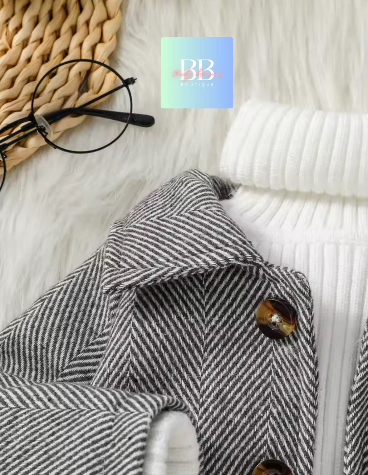 Gray herringbone coat with a button on a textured surface, featuring a brand logo in the corner.