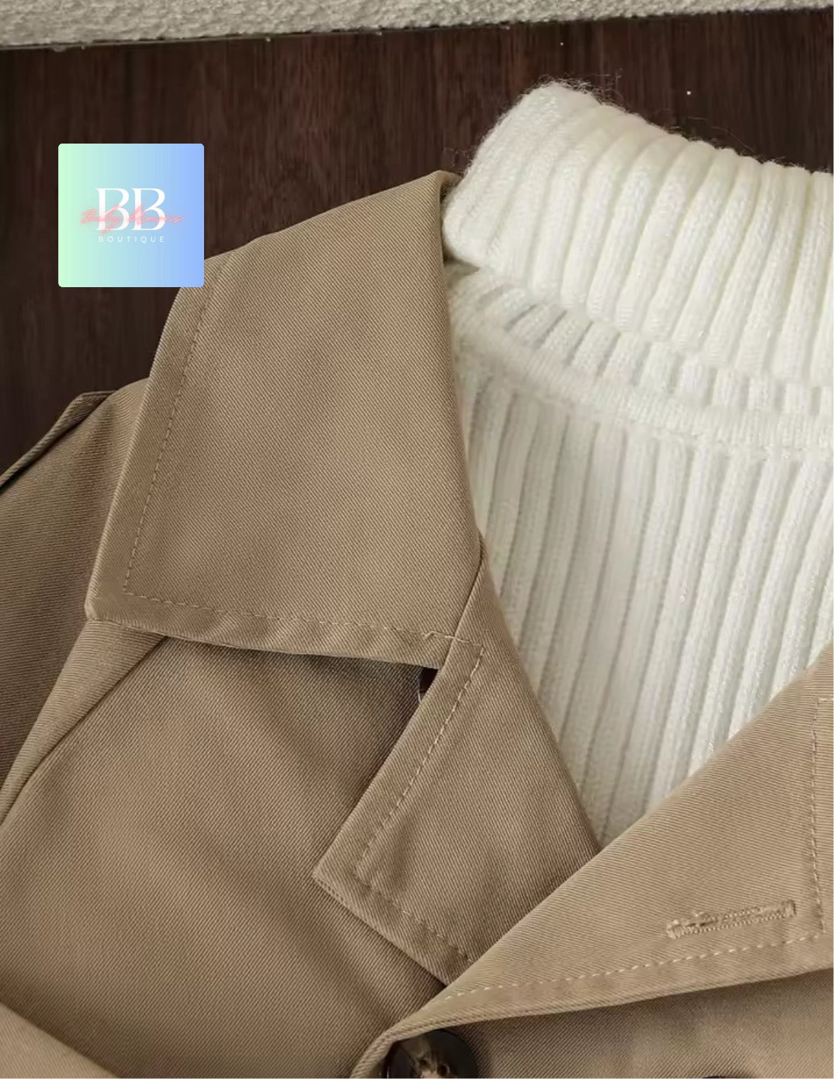 Close-up of a beige coat with a textured white sweater in the background