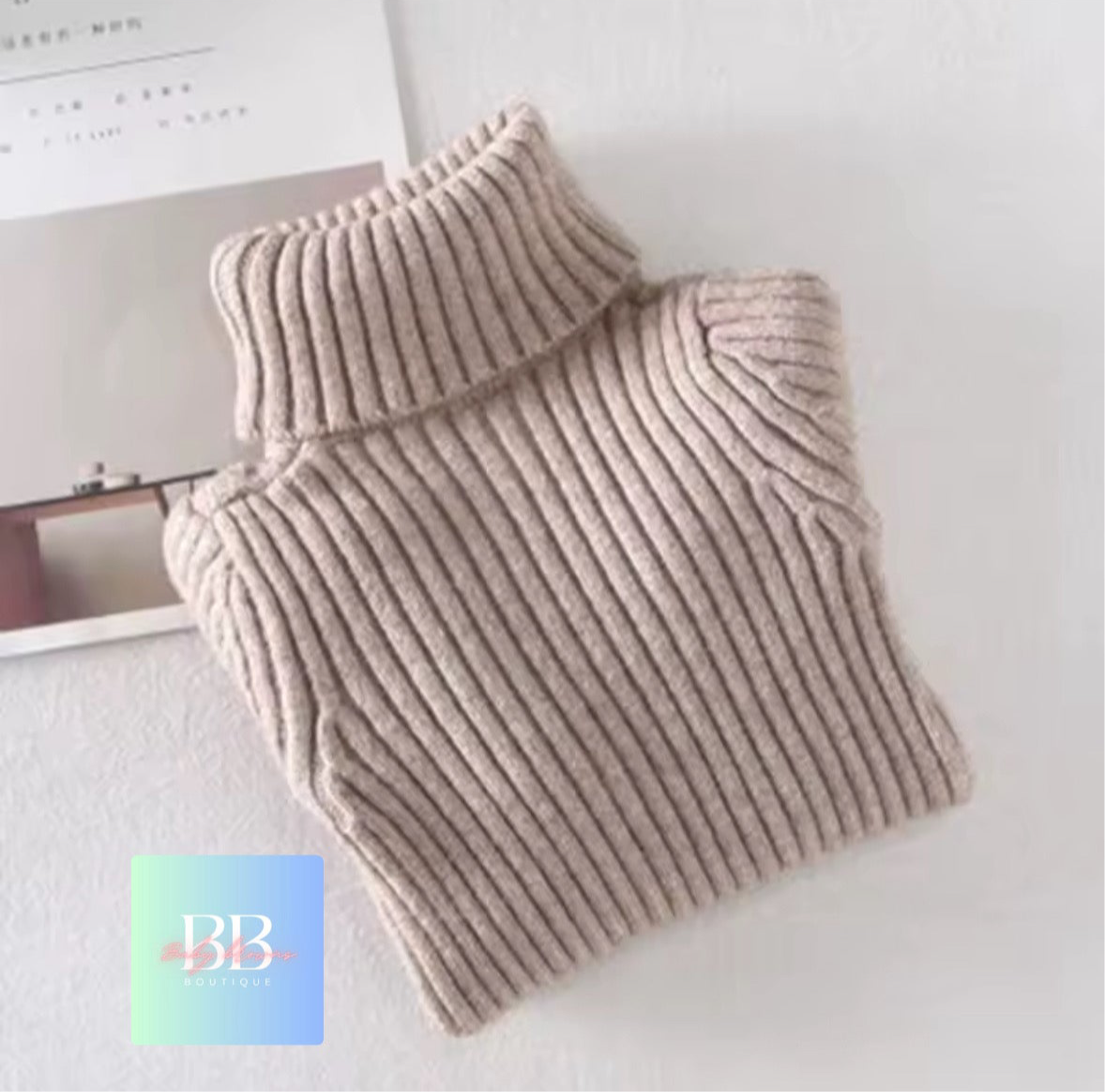 Beige ribbed sweater on a white surface with a brand logo in the corner.