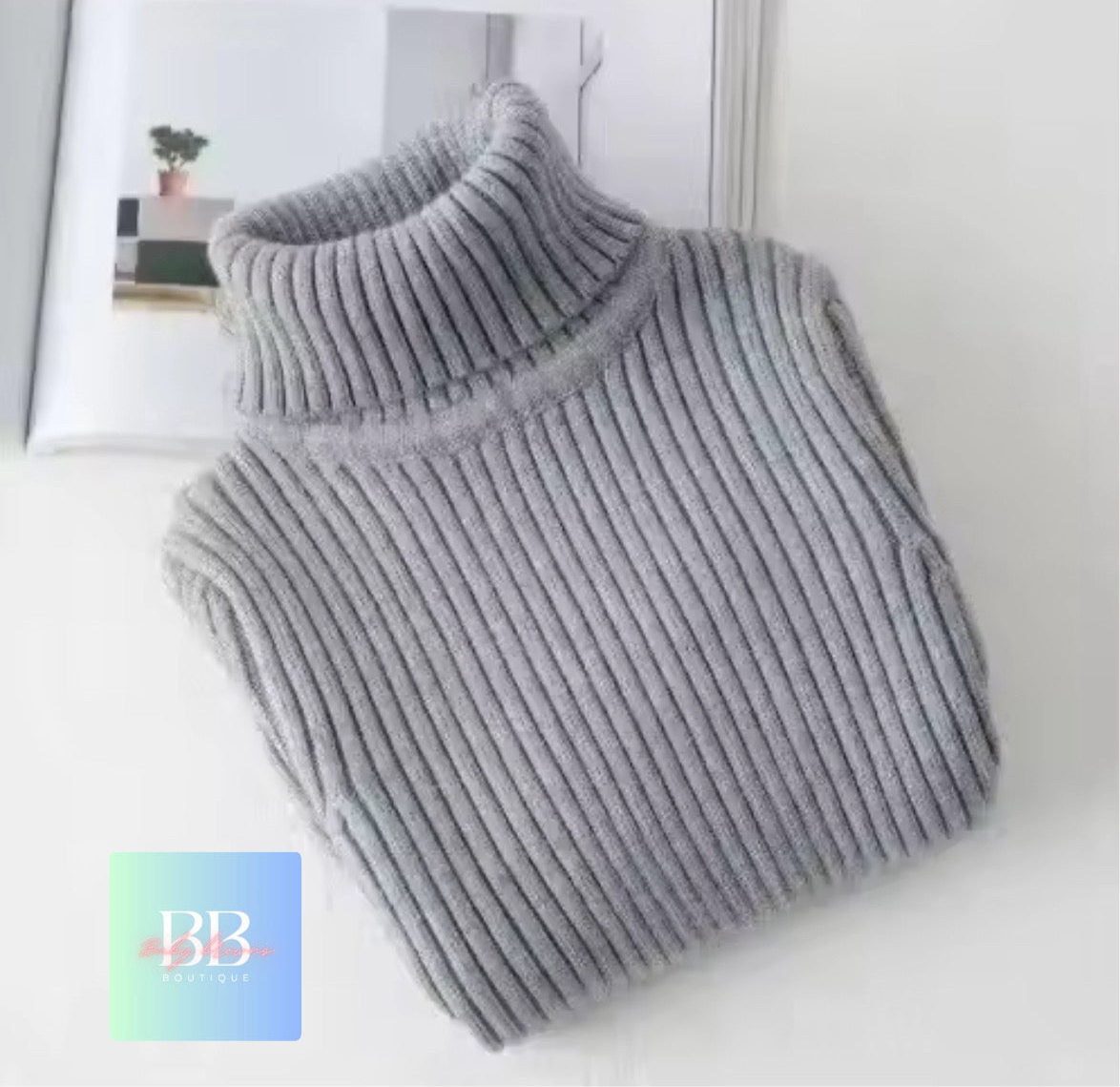Gray ribbed sweater on a white surface with a blurred background