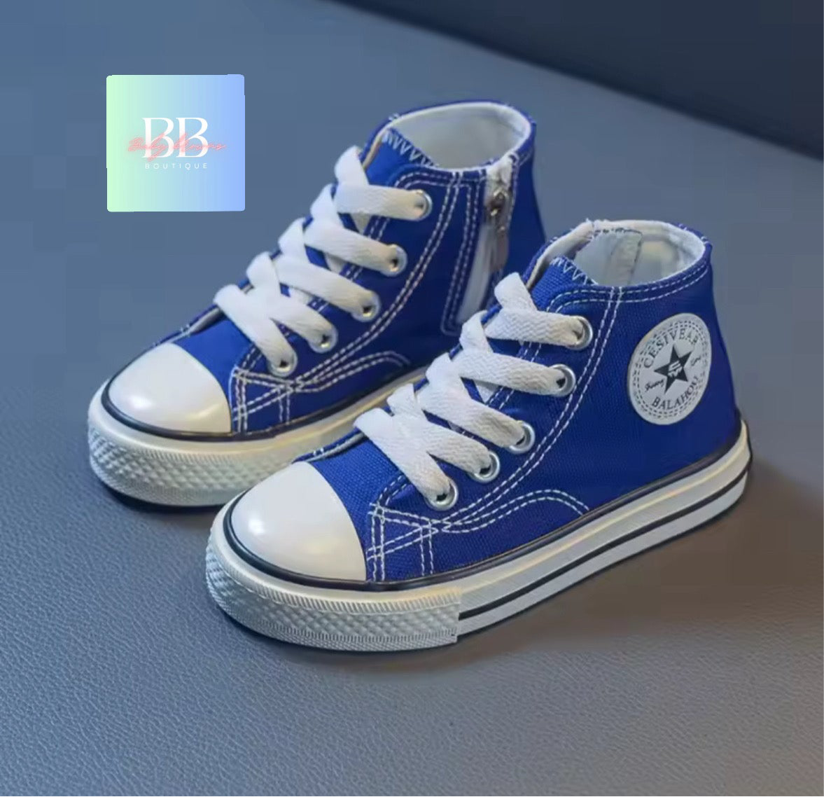 Blue high-top sneakers with white laces on a gray surface, featuring a brand logo in the corner.