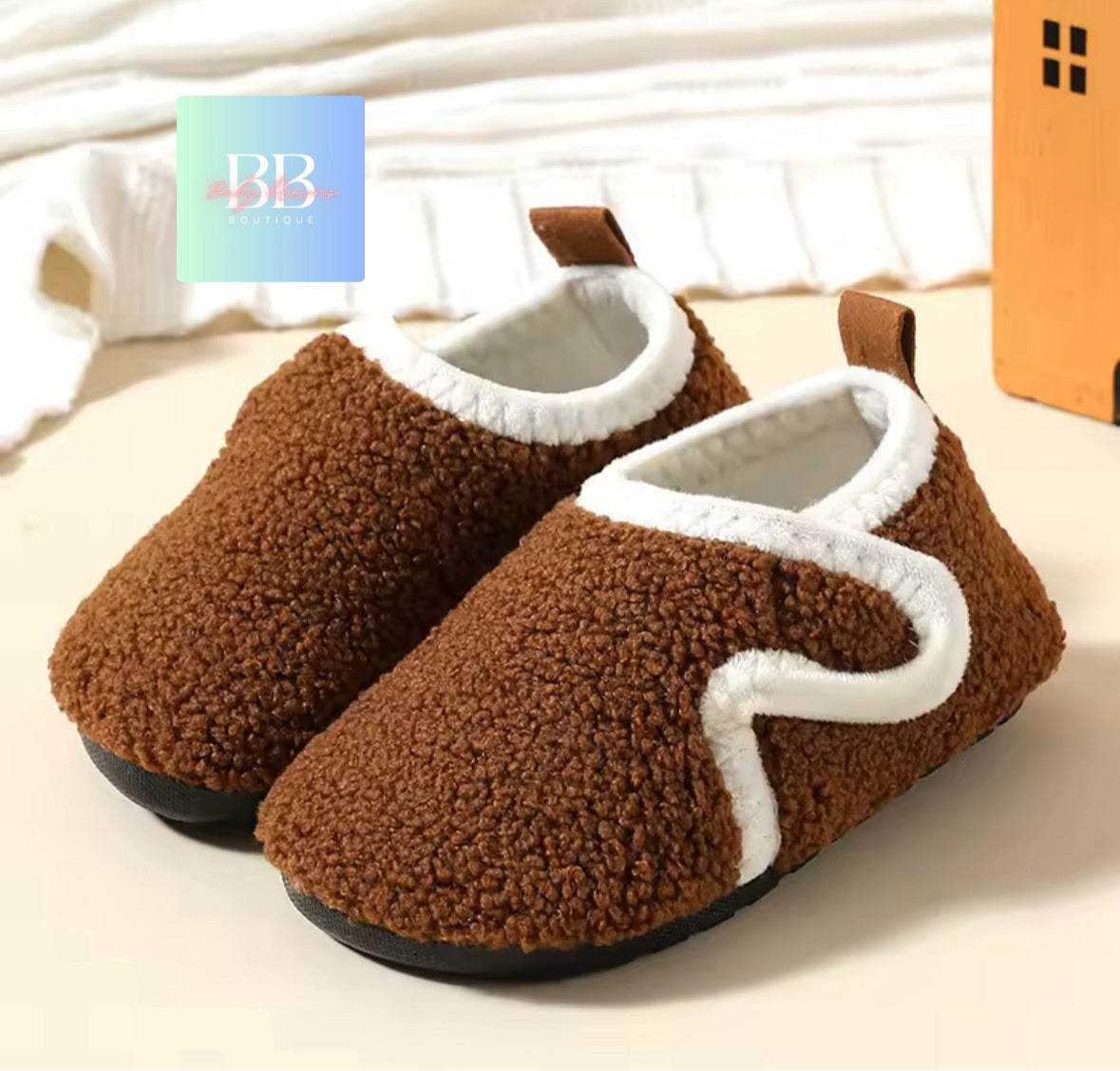 Brown slippers with white trim on a light background