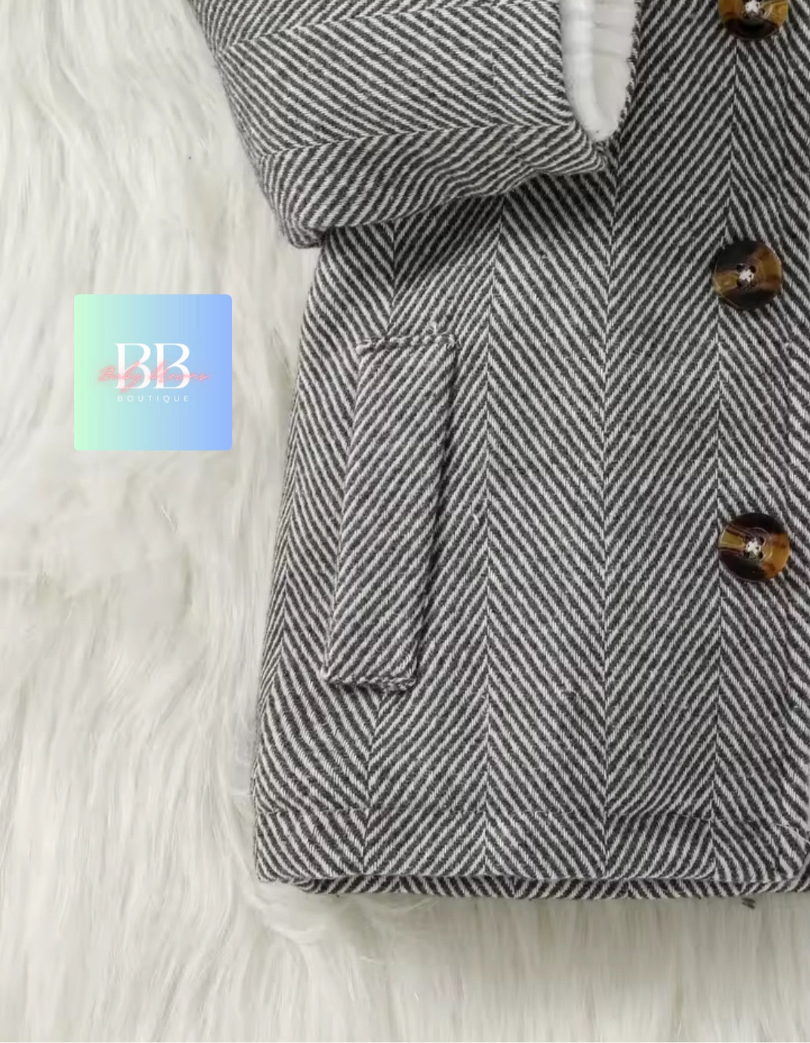 Herringbone-patterned coat with button details on a white fur background