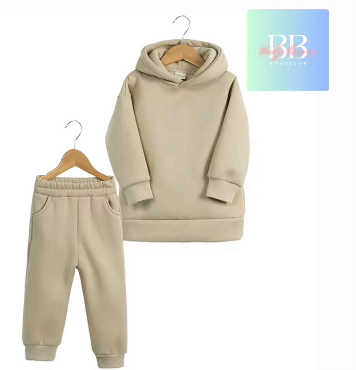 Beige hoodie and jogger pants set on hangers with a brand logo in the corner.