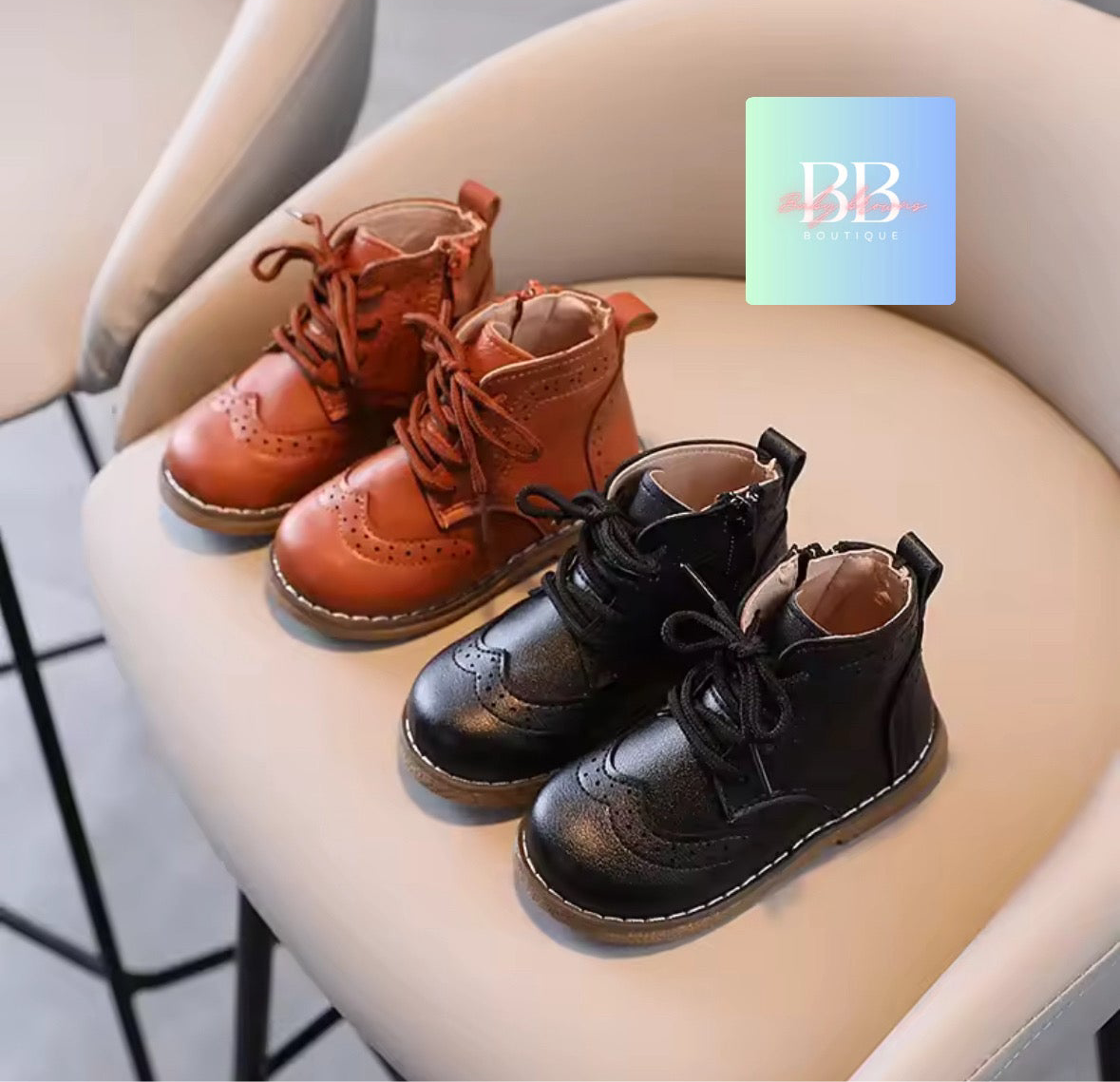 Pair of brown and black children's boots on a chair with a brand logo in the corner.