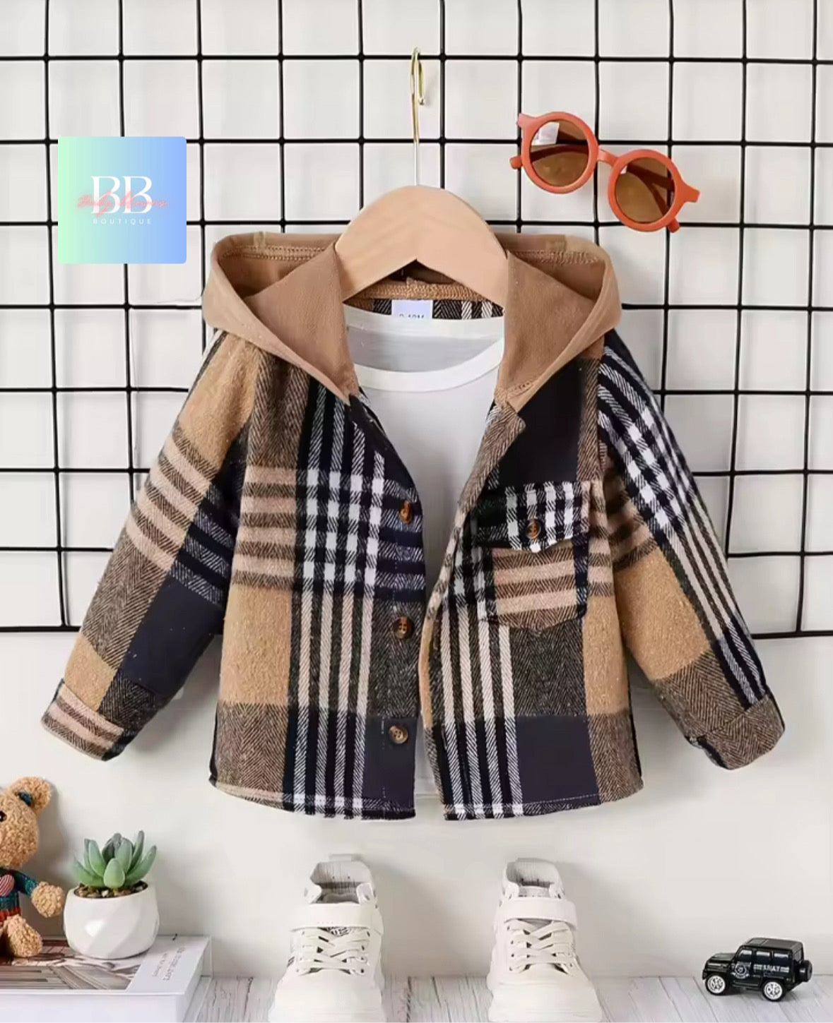 Plaid jacket on a hanger with a white shirt underneath, sunglasses above, and small toys below on a grid background.