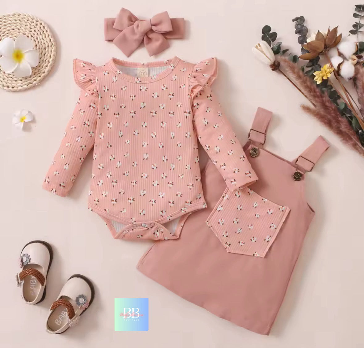 Pink baby outfit with romper, dress, shoes, and headband on a light background