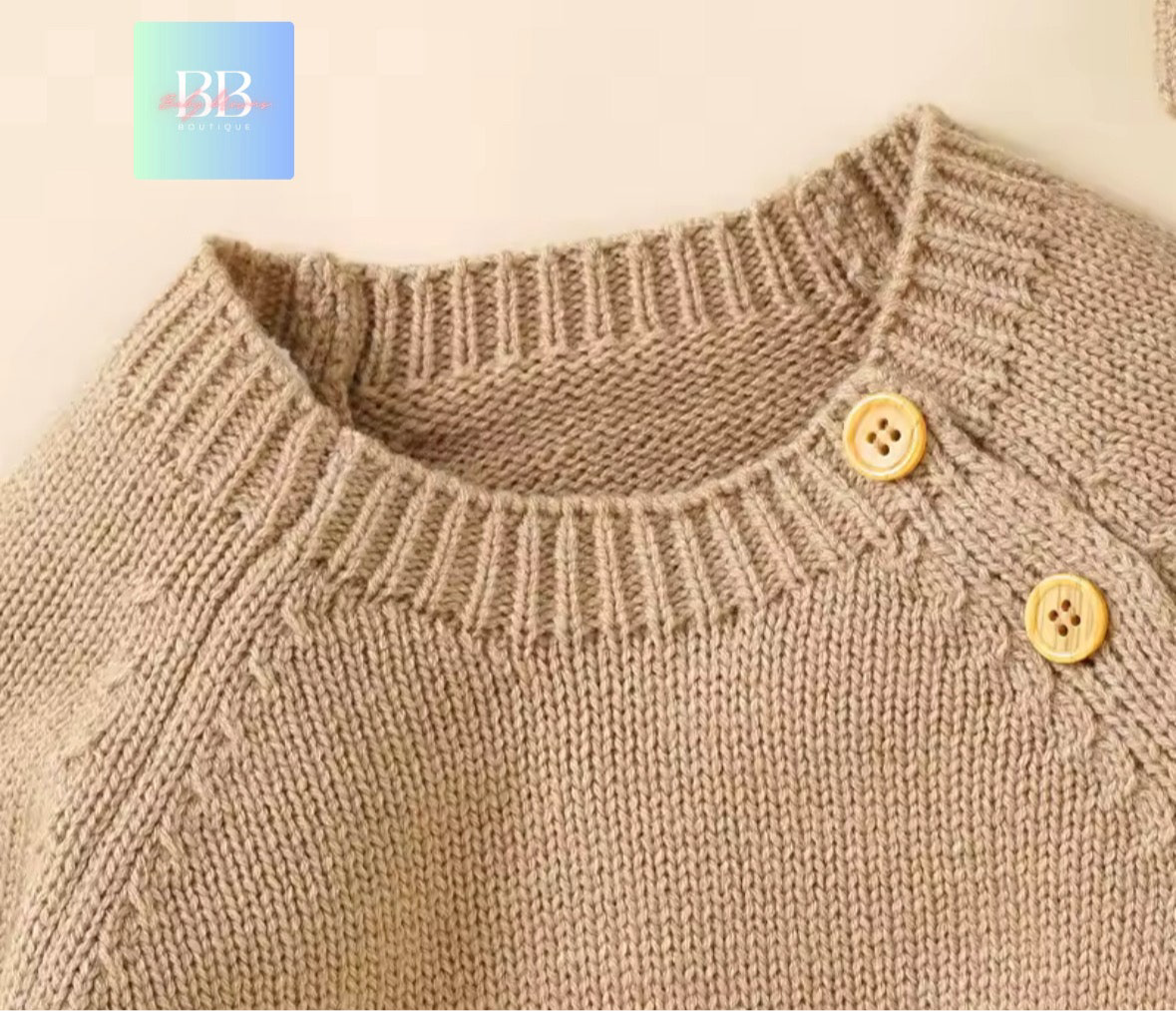 Close-up of a brown knitted sweater with buttons on a beige background