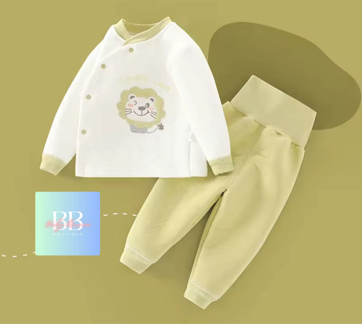 Baby outfit with white shirt and beige pants on a green background, featuring a lion design on the shirt.