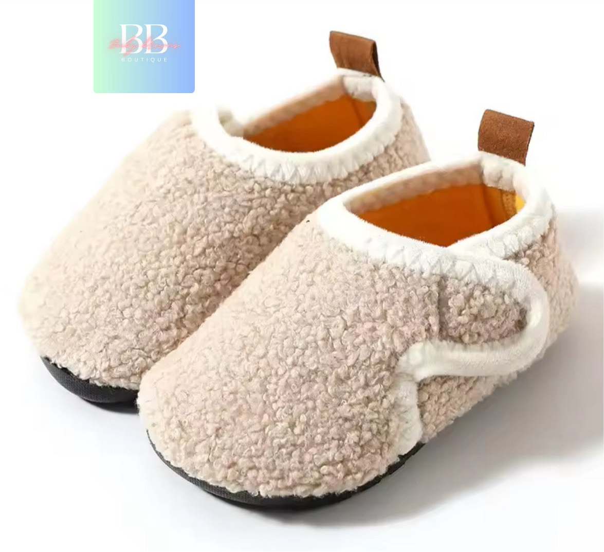 Pair of beige slippers with brown accents on a white background