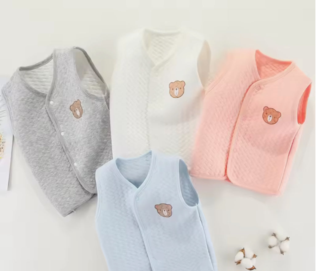 Four baby vests in gray, white, blue, and pink with bear embroidery on a light background. Soft cotton waistcoat/bodywarmer