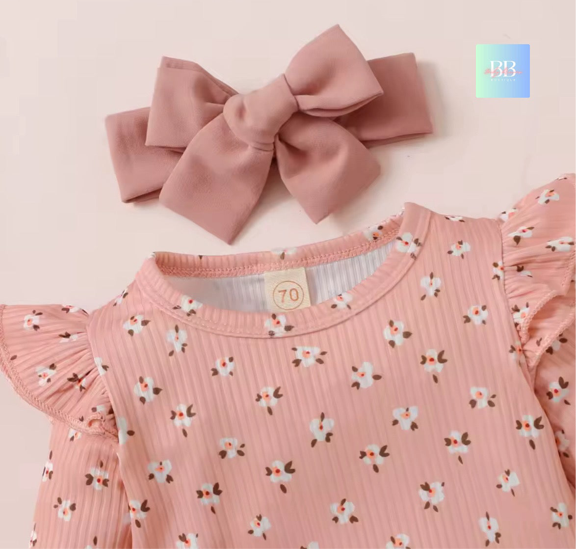 Pink children's top with floral pattern and matching headband on a light pink background