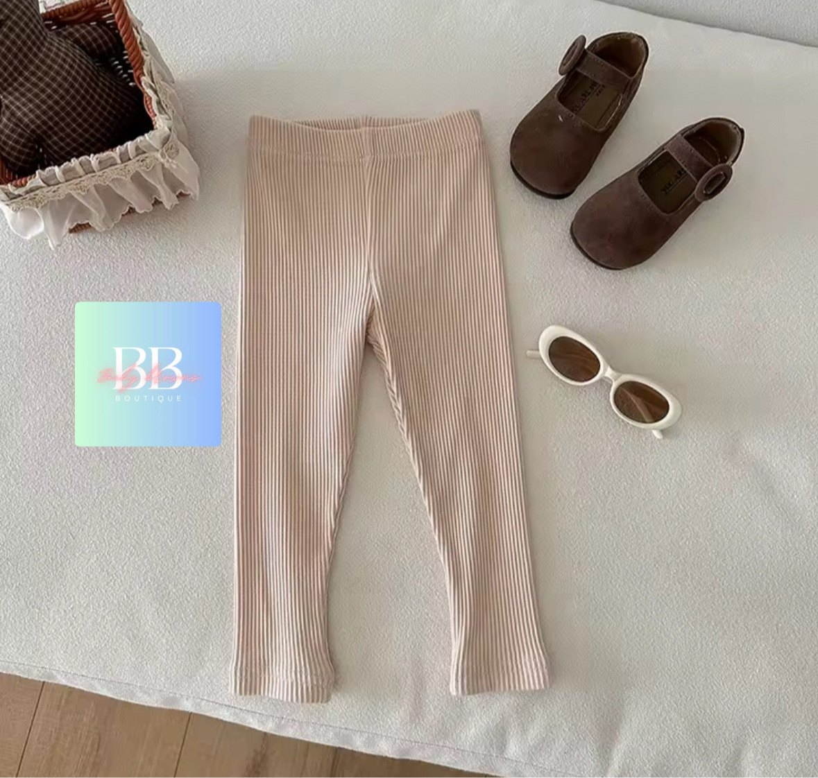 Beige leggings with brown shoes and sunglasses on a light surface, with a card featuring 'BB' branding.
