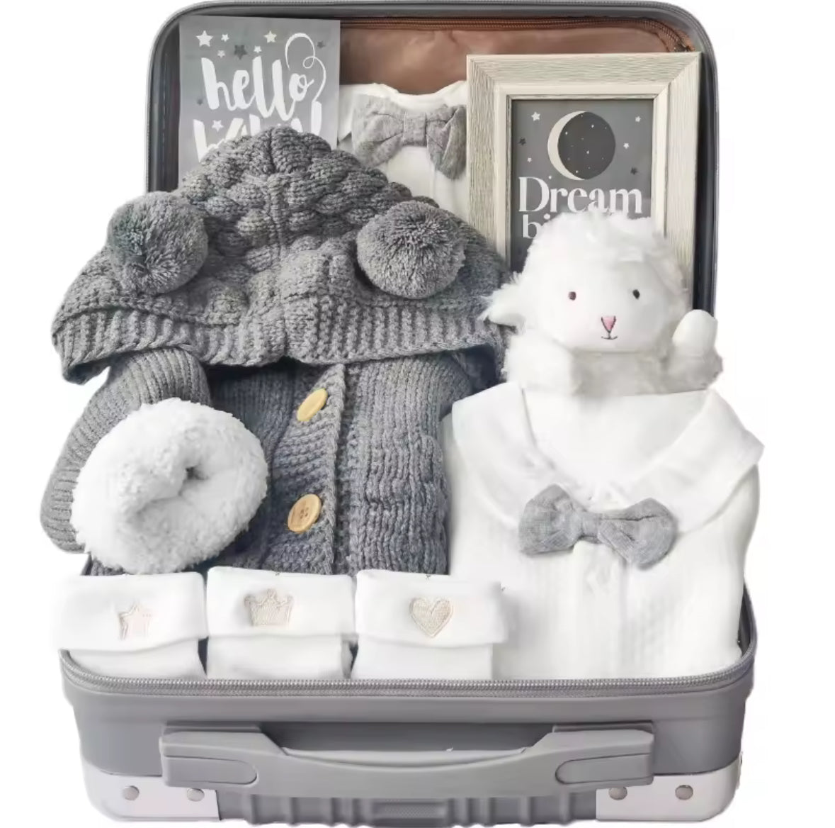 Baby gift set with knitted items, a teddy bear, and a photo frame in an open suitcase.