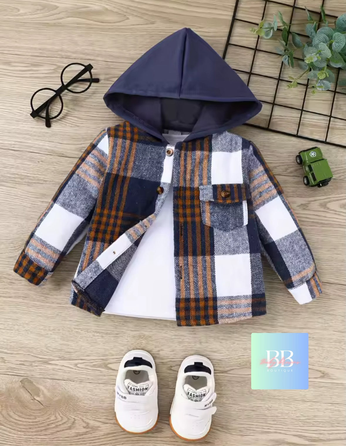 Plaid shirt with hood, shoes, and glasses on a wooden surface