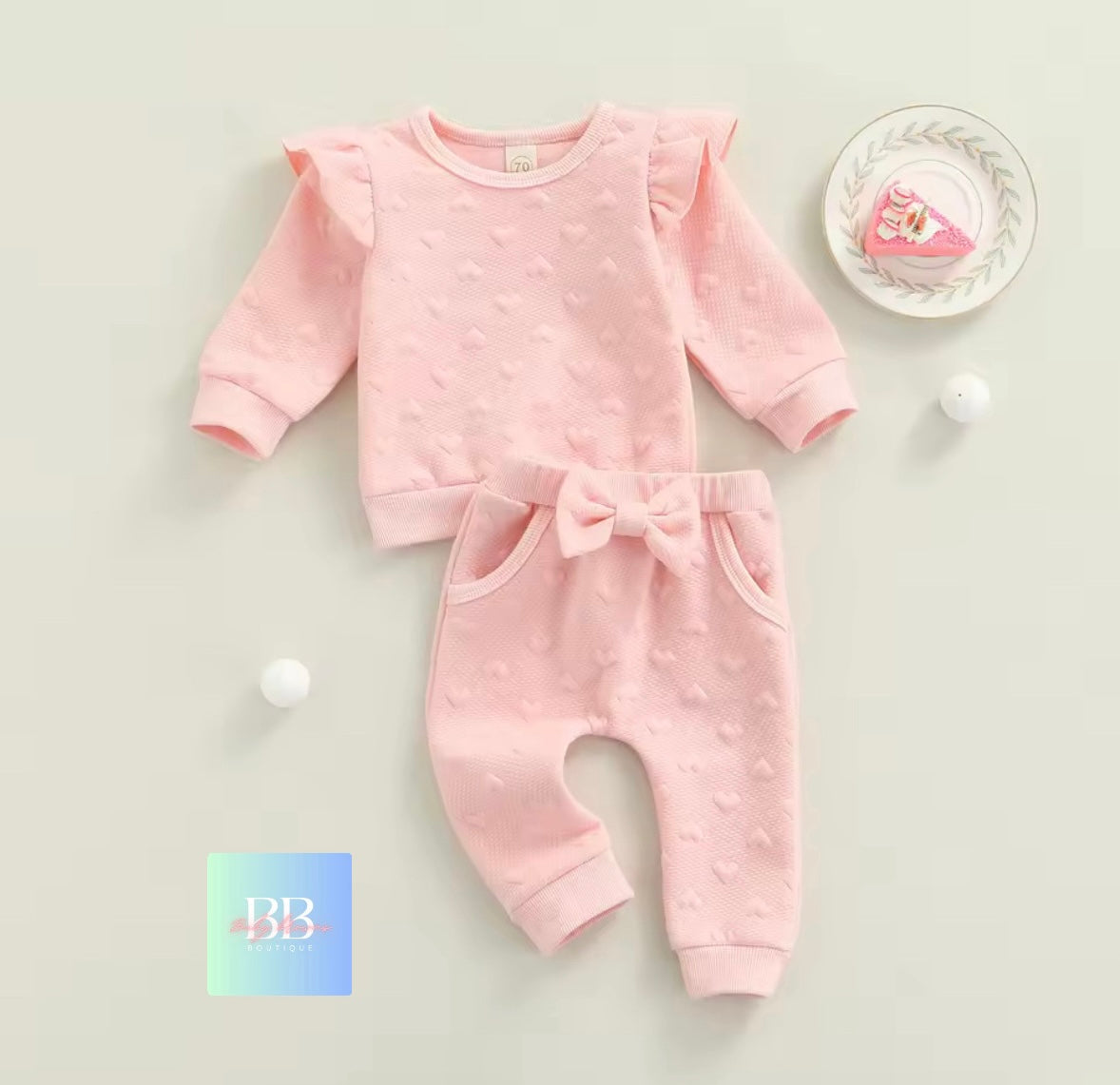 Pink baby outfit with a bow on a light gray background
