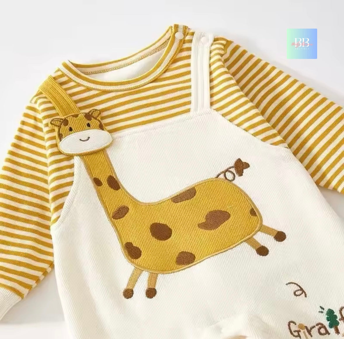 Baby outfit with yellow and white striped long-sleeve shirt and white bib with giraffe design on a light gray background.