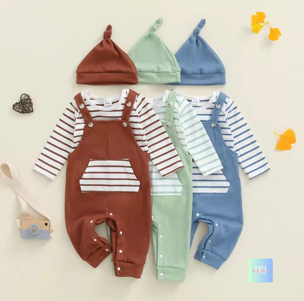 Set of baby outfits with brown, green, and blue overalls and hats on a light background.