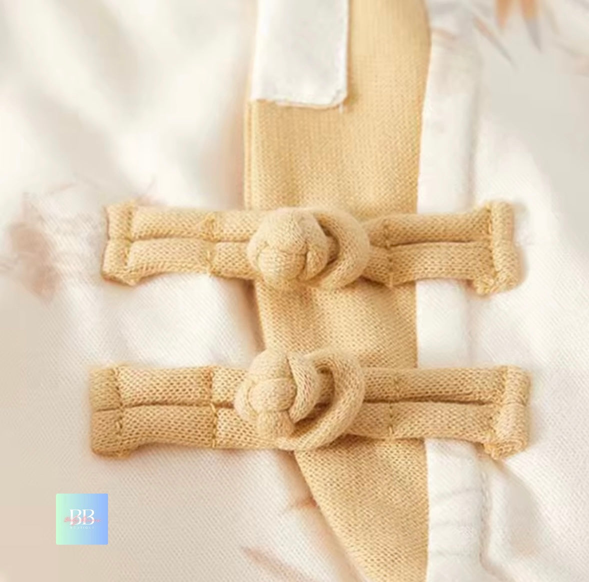 Beige knitted belt with decorative knots on a white background