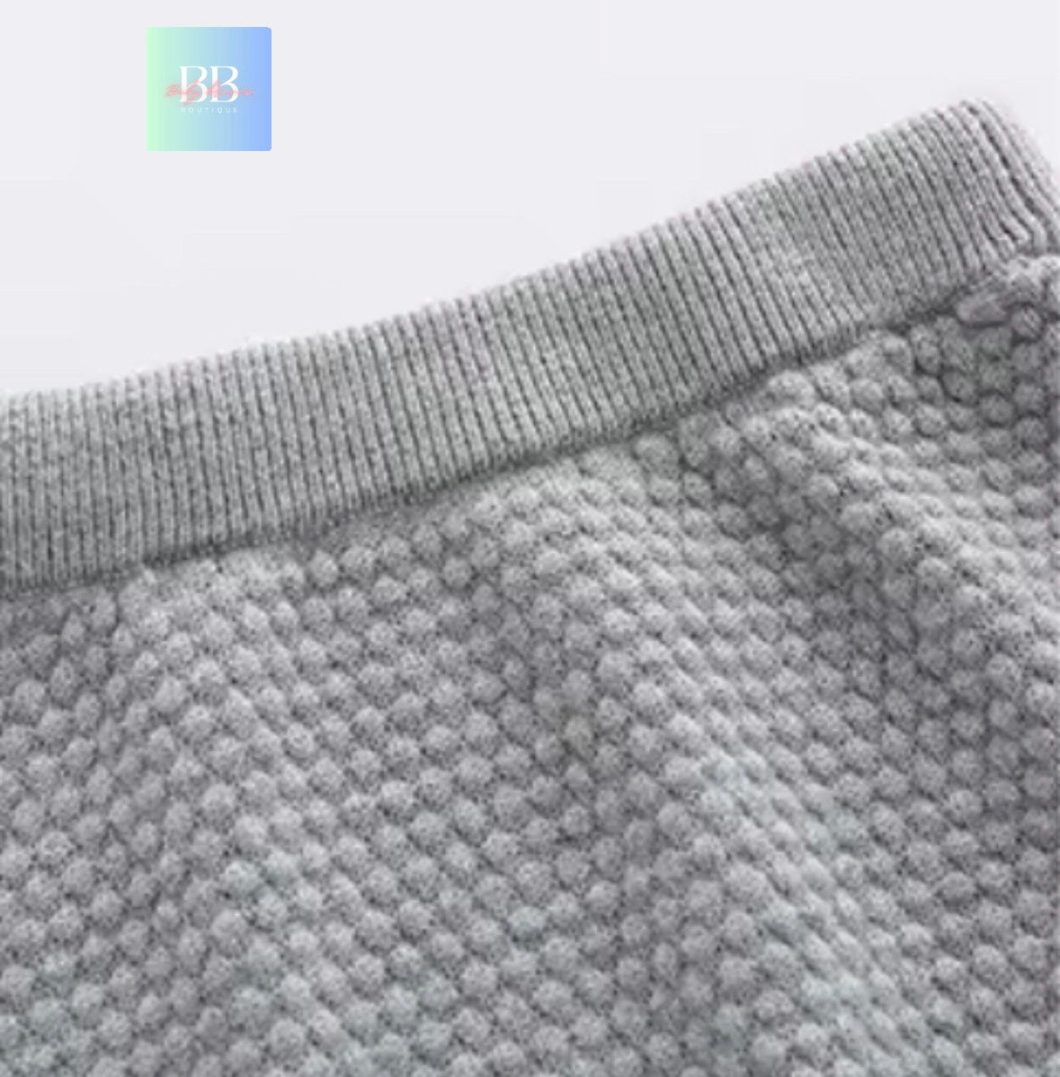 Close-up of a textured gray fabric with a brand logo in the corner.