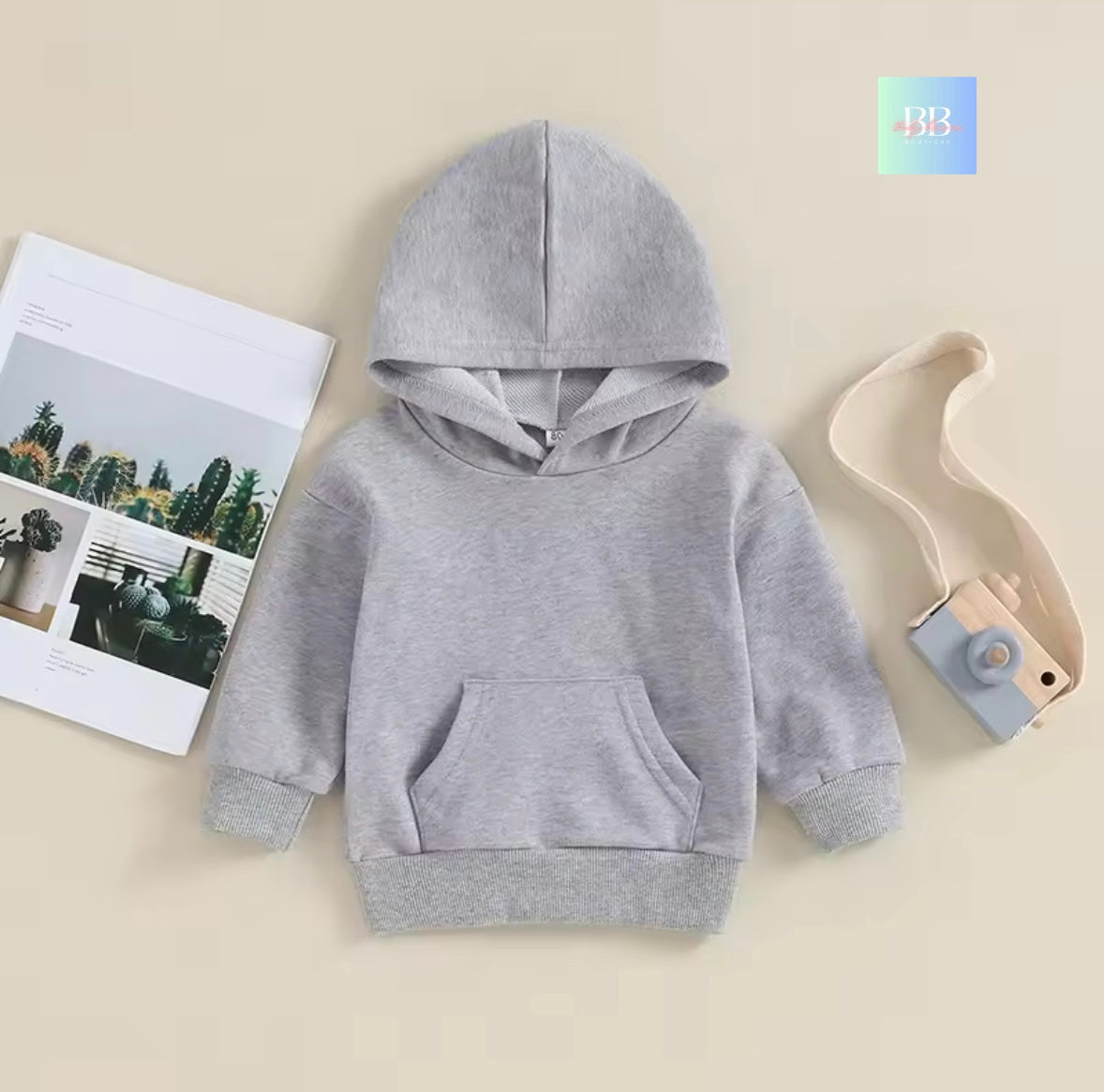 Gray hoodie on a beige background with a magazine and toy.