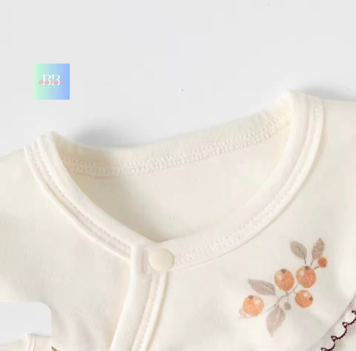 Close-up of a baby outfit with floral embroidery on a white background