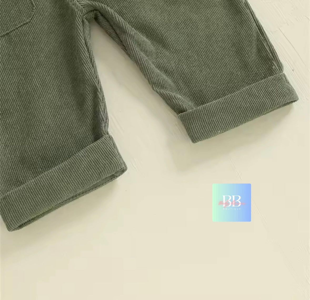 Green corduroy pants on a light beige background with a brand logo in the corner.