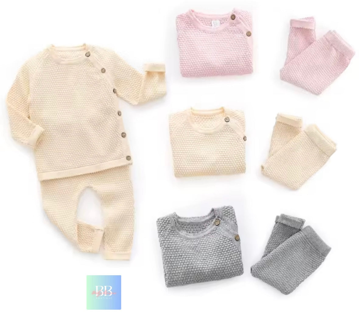 Collection of folded baby clothes including sweaters and pants on a white background