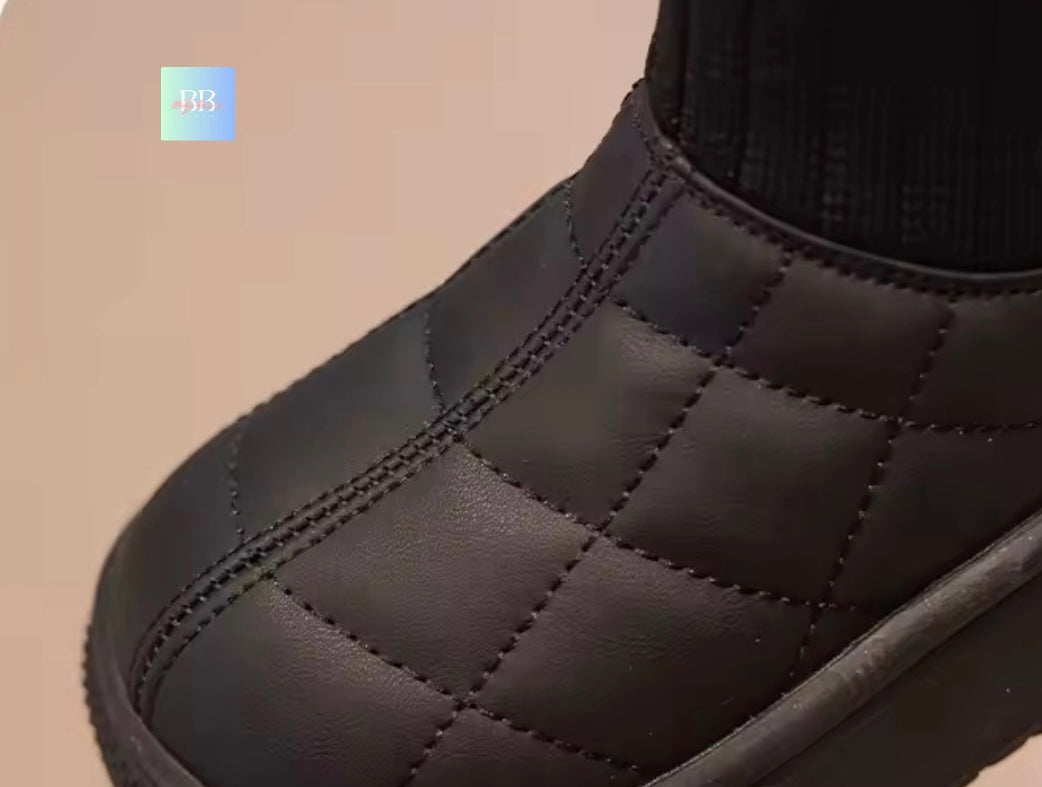 Close-up of a black quilted boot on a beige background