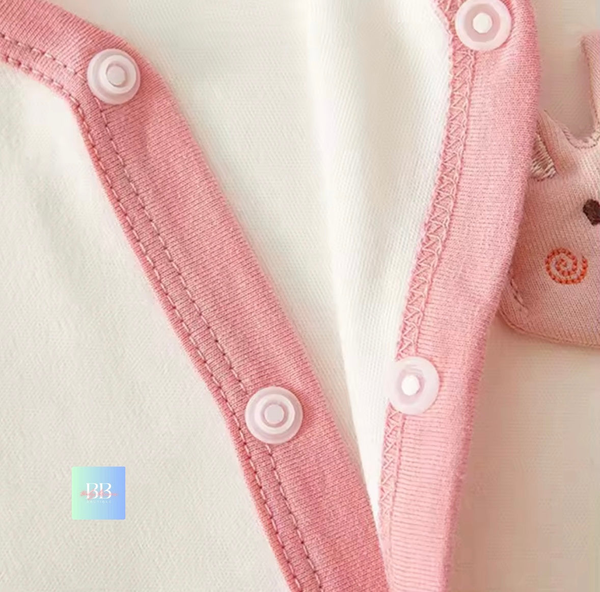 Close-up of pink baby romper with buttons on a white background