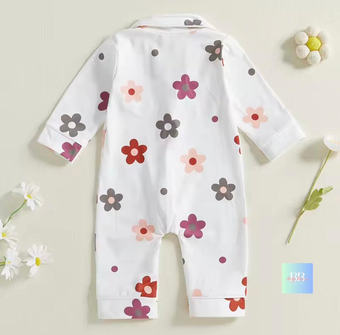 White baby onesie with colorful floral pattern on a light beige background
