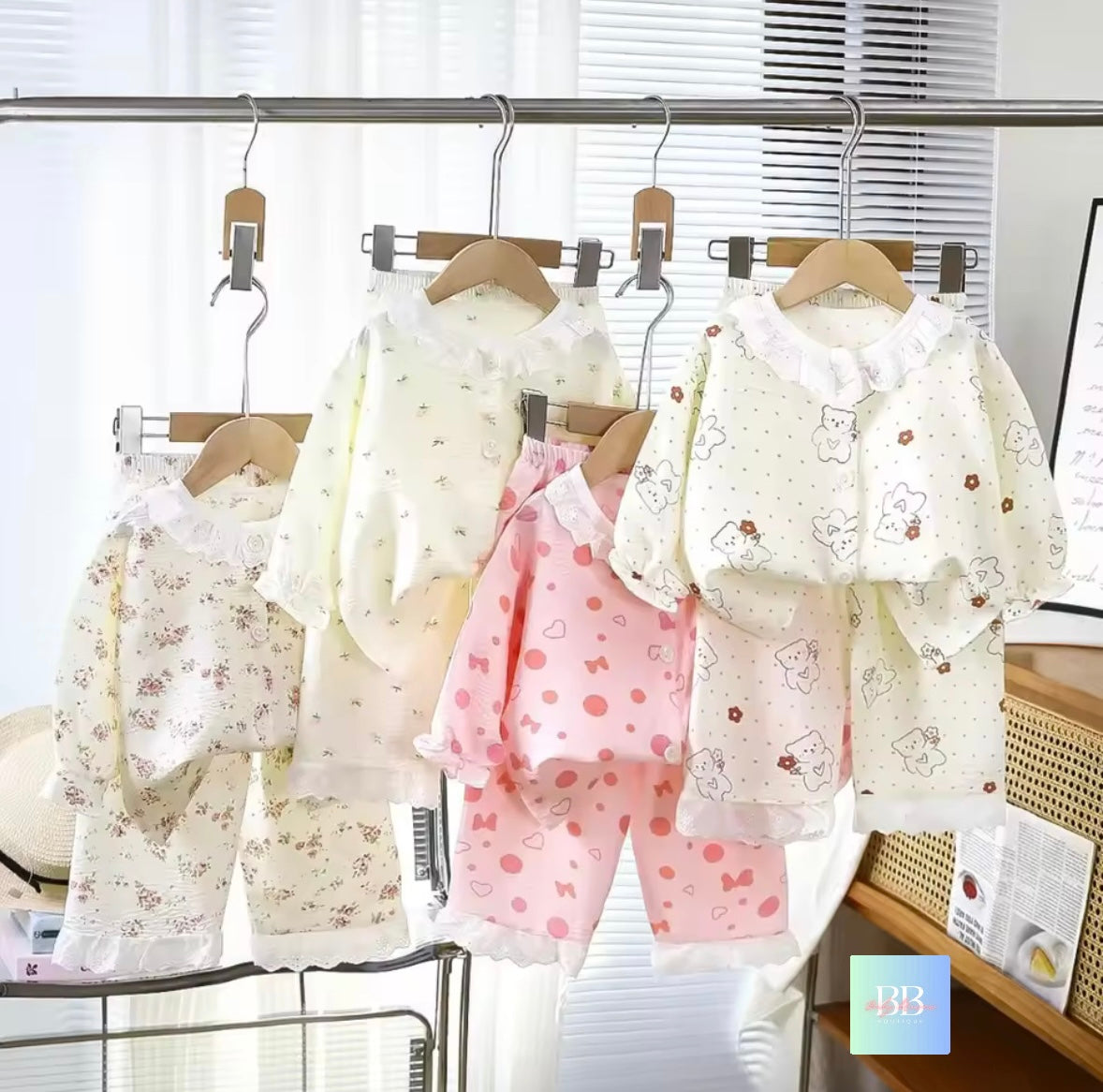 Children's clothing set with floral patterns on hangers against a white background