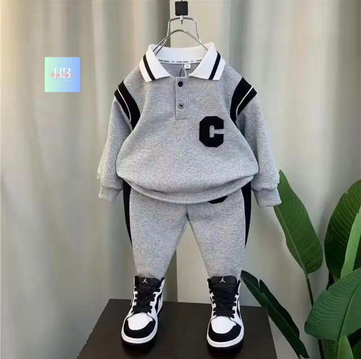 Children's gray outfit with black and white accents on a stand against a neutral background.