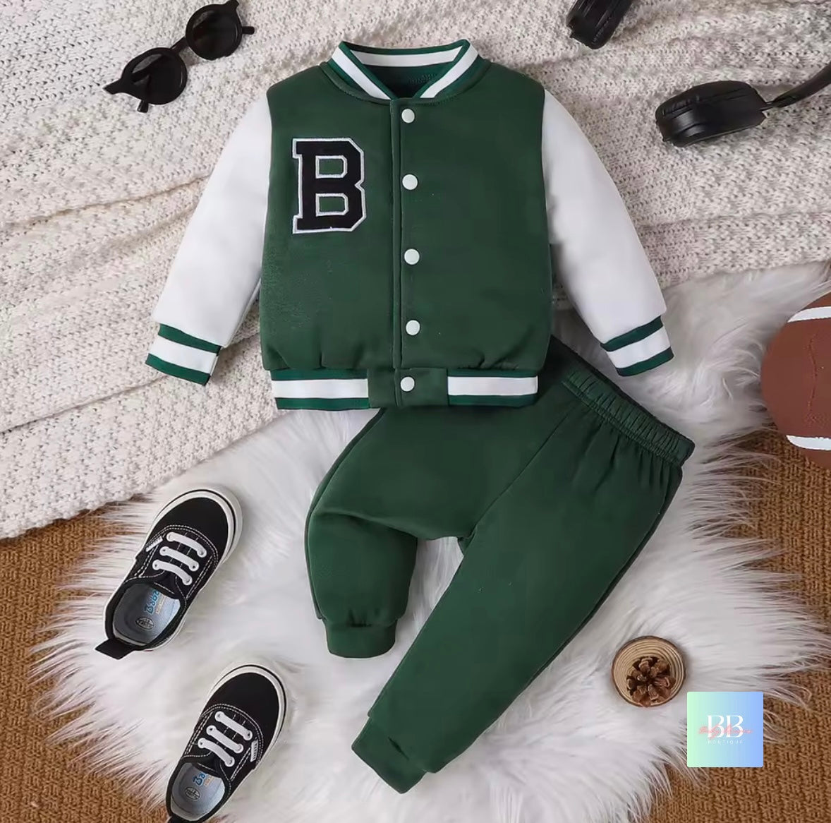 Green varsity jacket and pants set with shoes on a textured surface