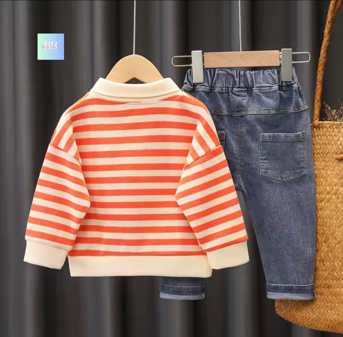 Striped sweater and jeans on hangers against a dark curtain background