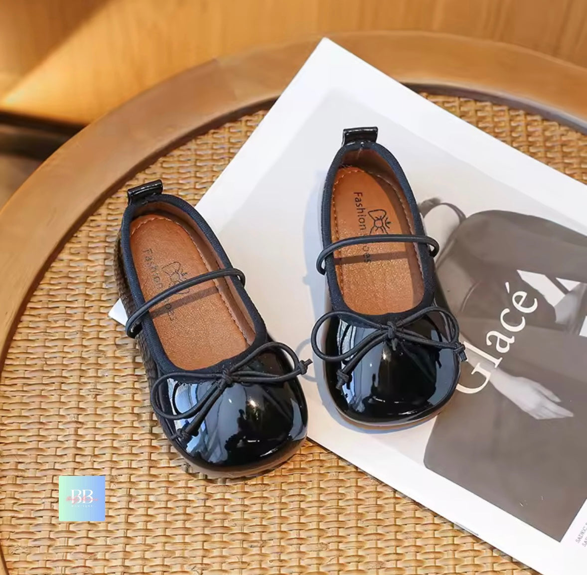 Black patent leather shoes with a bow on a woven surface