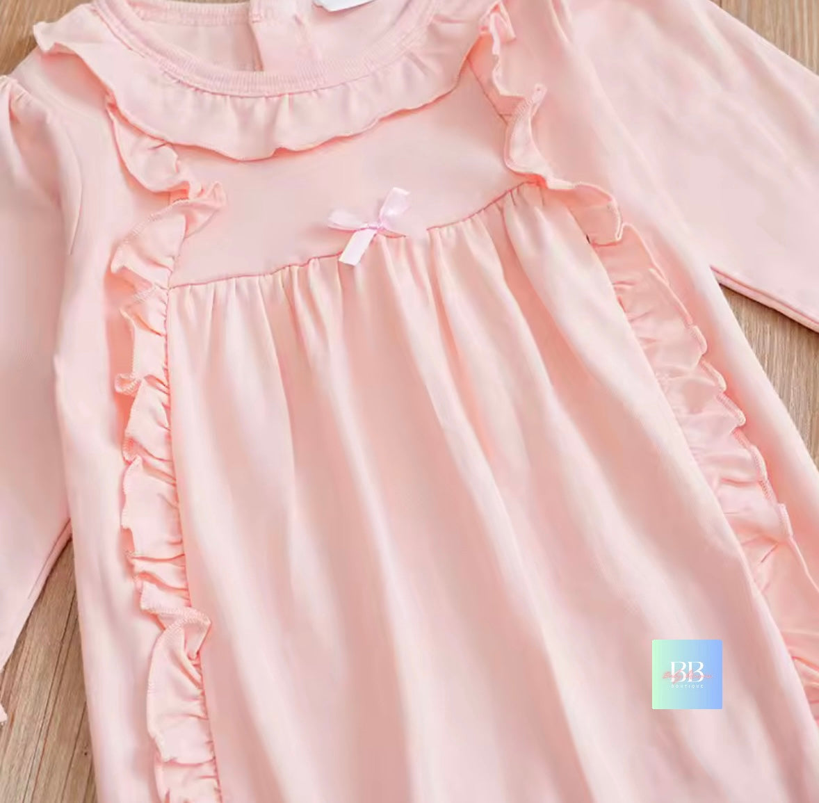 Pink baby dress with ruffles on a wooden surface