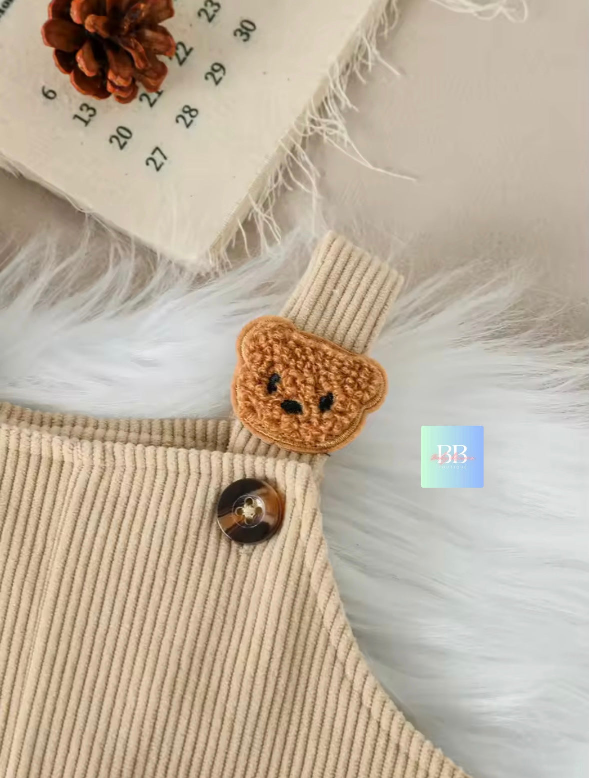 Close-up of a textured fabric surface with a knitted bear button and a calendar in the background.