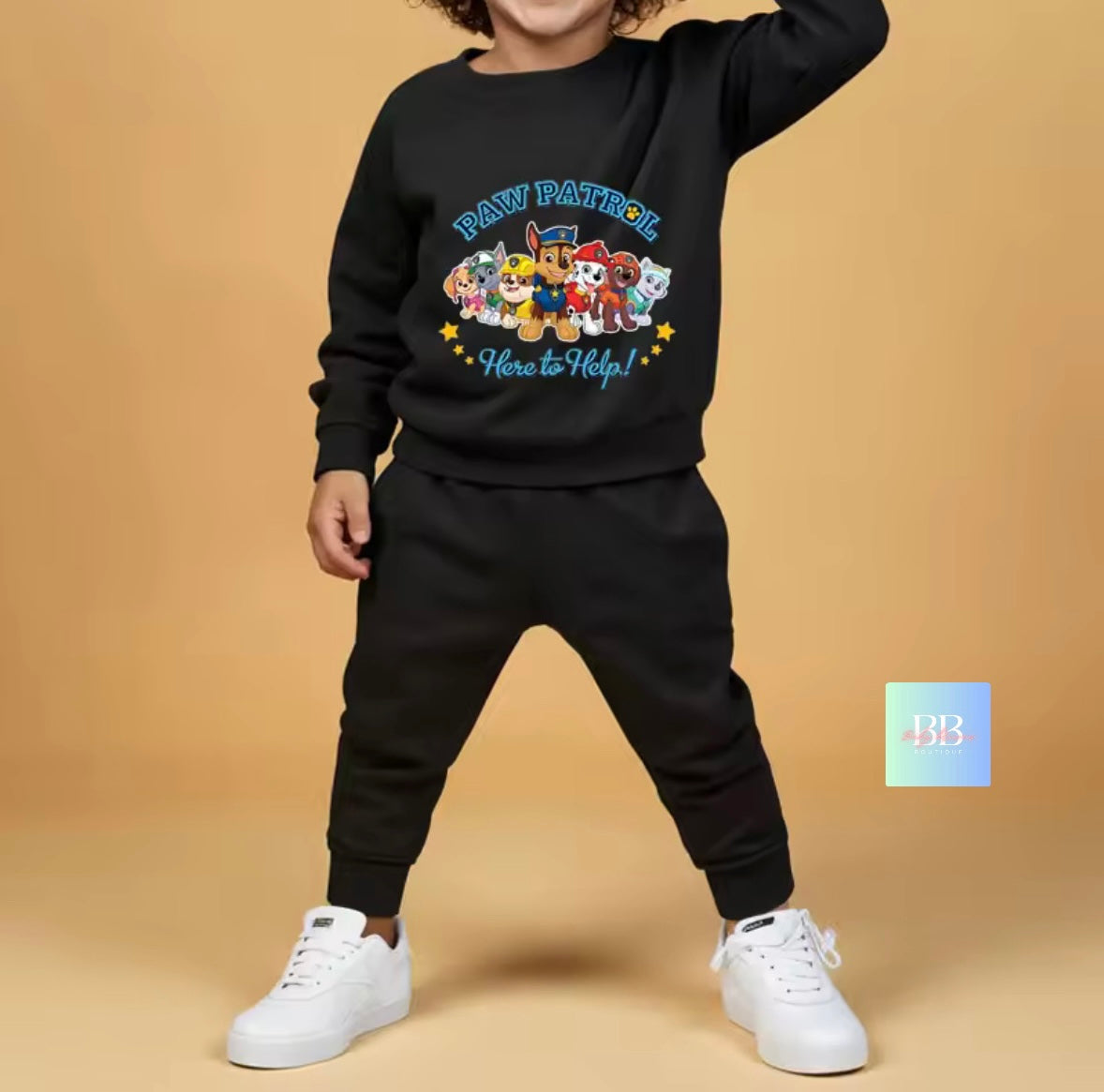 Child wearing a black 'Paw Patrol' sweatshirt and pants on a beige background