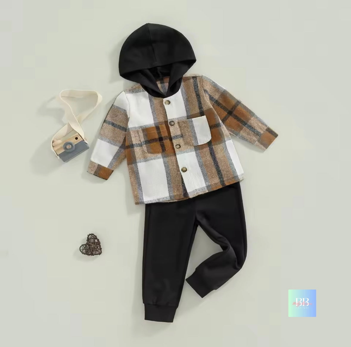 Children's outfit with plaid shirt, black pants, and black hood on a light gray background