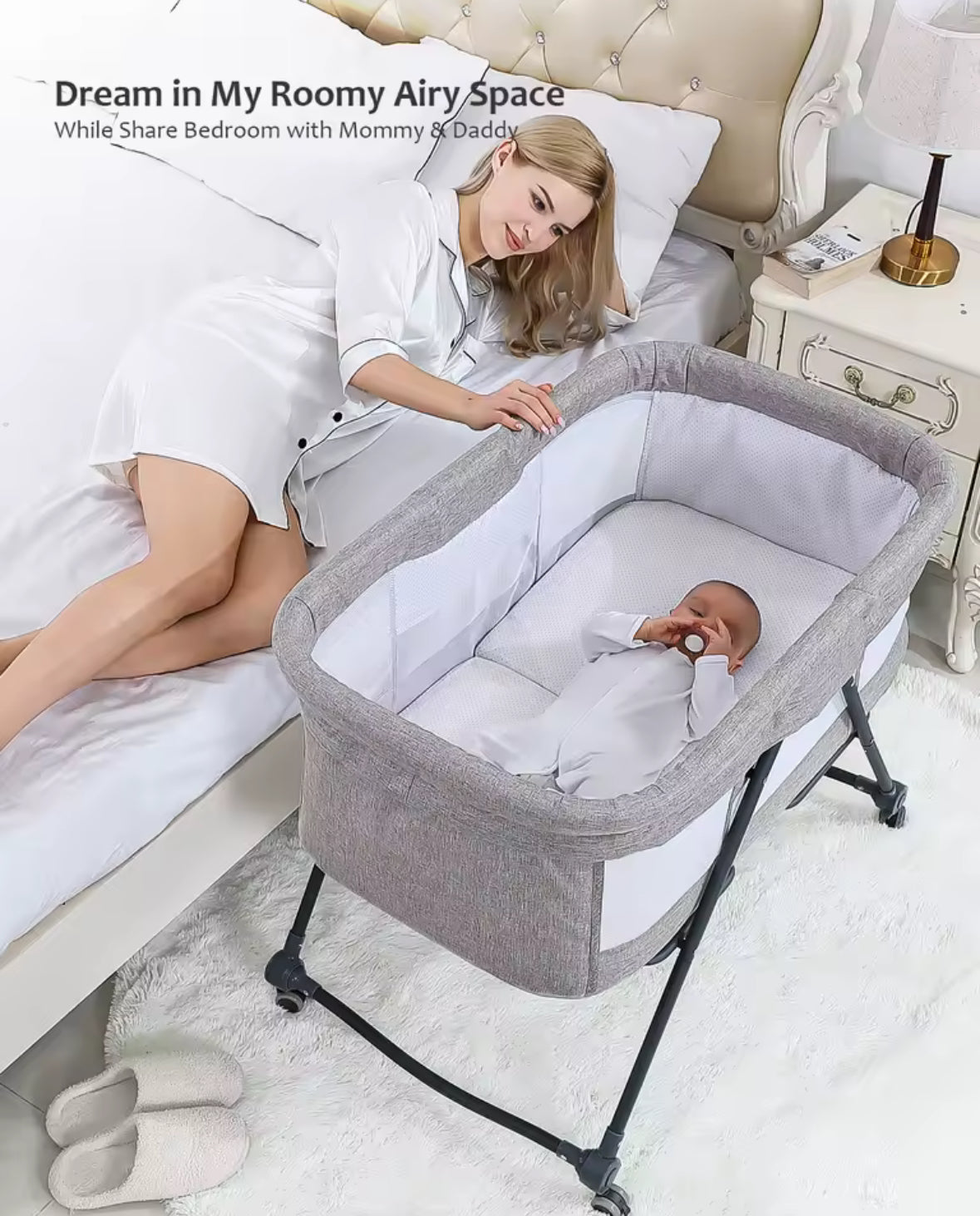 Woman sitting on a bed with a baby in a portable crib, in a bedroom setting.