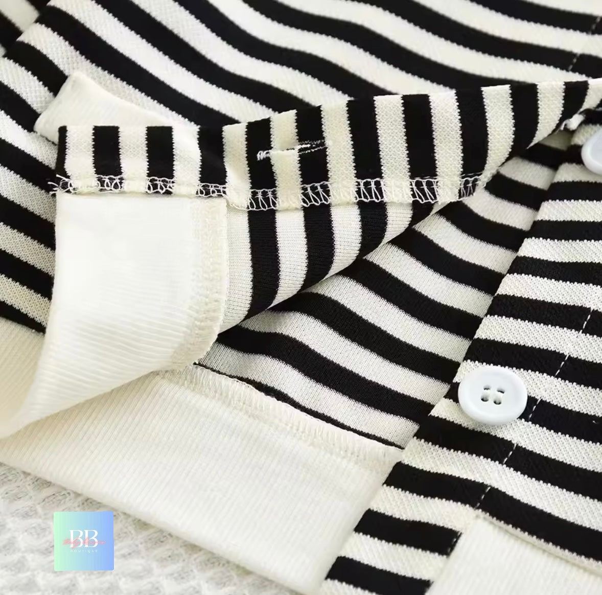 Close-up of black and white striped fabric with a button, on a textured surface.