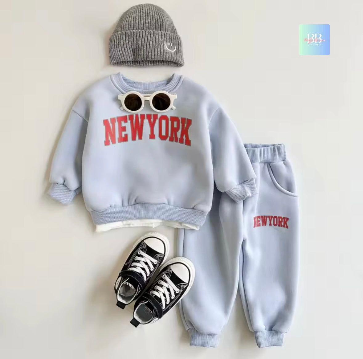 Children's outfit with 'NEW YORK' sweatshirt and pants, gray beanie, and black sneakers on a light background.