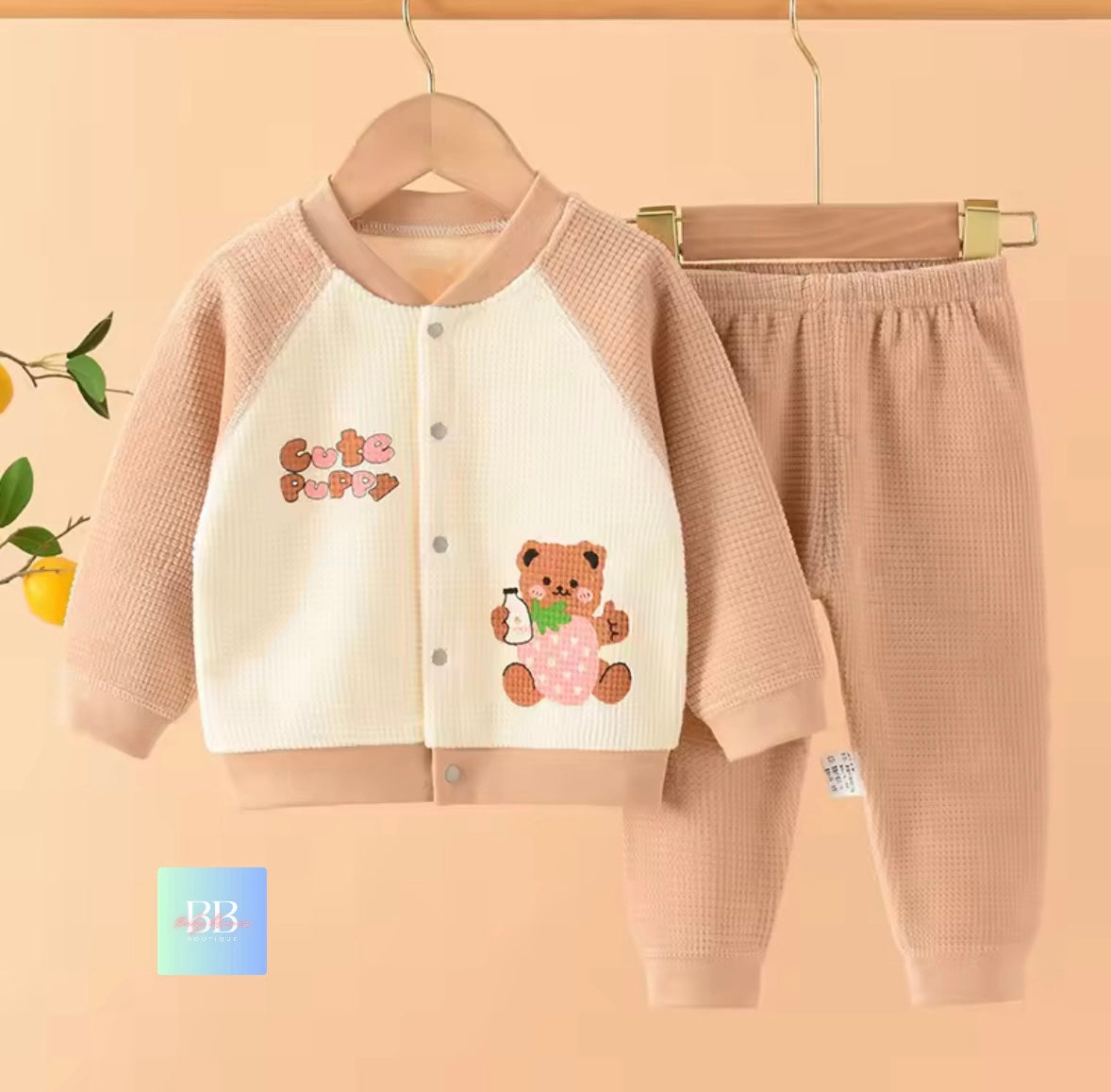 Children's outfit with jacket and pants on a hanger against a beige background