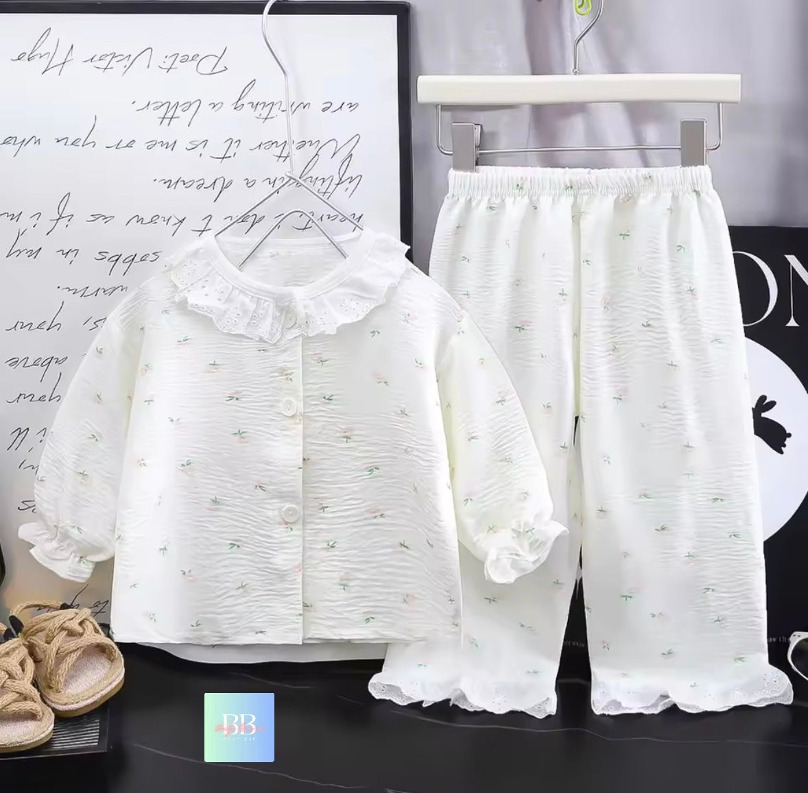 White lace outfit with a shirt and pants on a black surface with text in the background