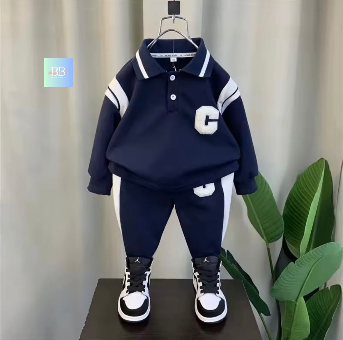 Navy blue children's outfit with white accents on a hanger against a neutral background.