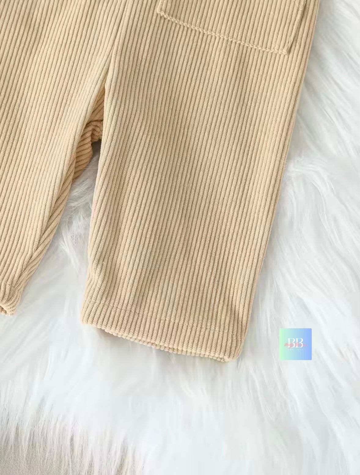 Beige ribbed pants on a white fur surface