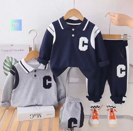 Children's clothing set with navy and gray sweaters and pants on hangers against a light background.