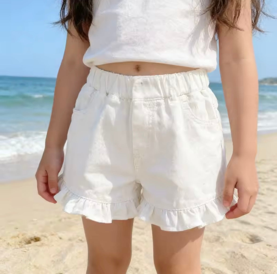 Person wearing white shorts and a white top on a beach