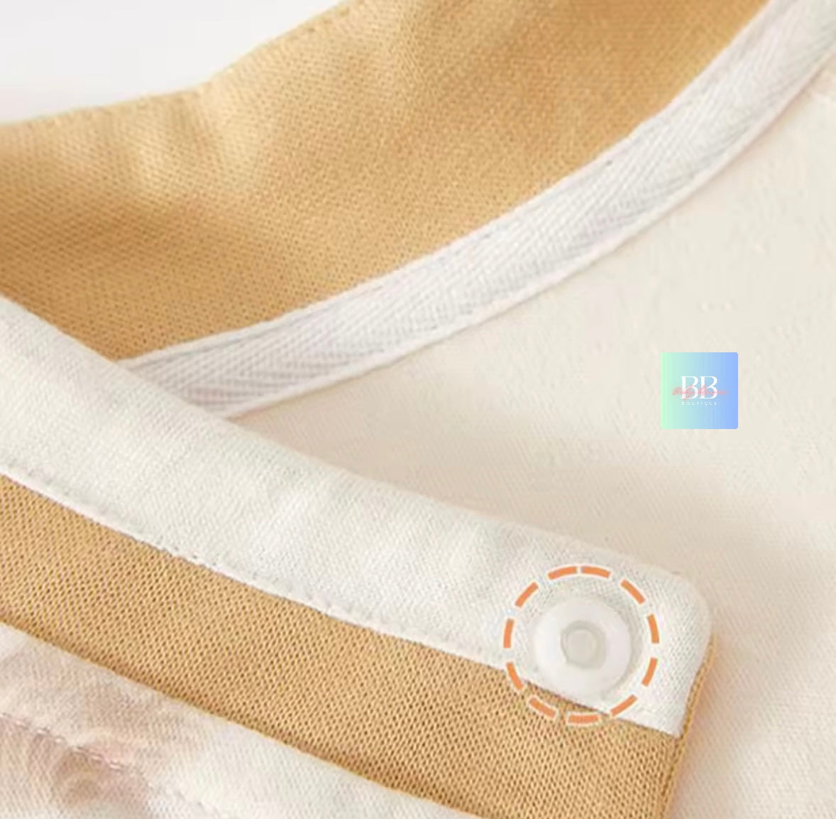 Close-up of a beige and white fabric with a button, likely from a baby garment.